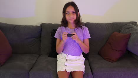 hispanic kid girl gamer playing relaxing video games on sofa