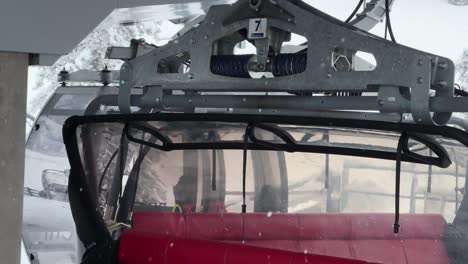 snowy ski lift with red seats ascending a mountain on a cloudy winter day