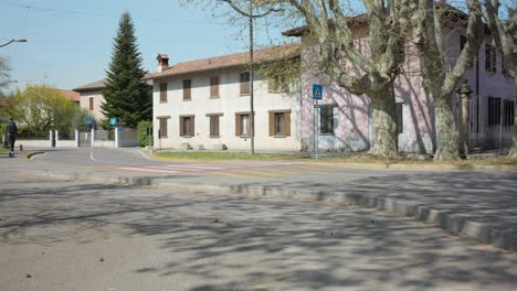 Hombre-Con-Casco-Montando-Un-Scooter-Eléctrico-Y-Moviéndose-Por-Un-Barrio-Residencial