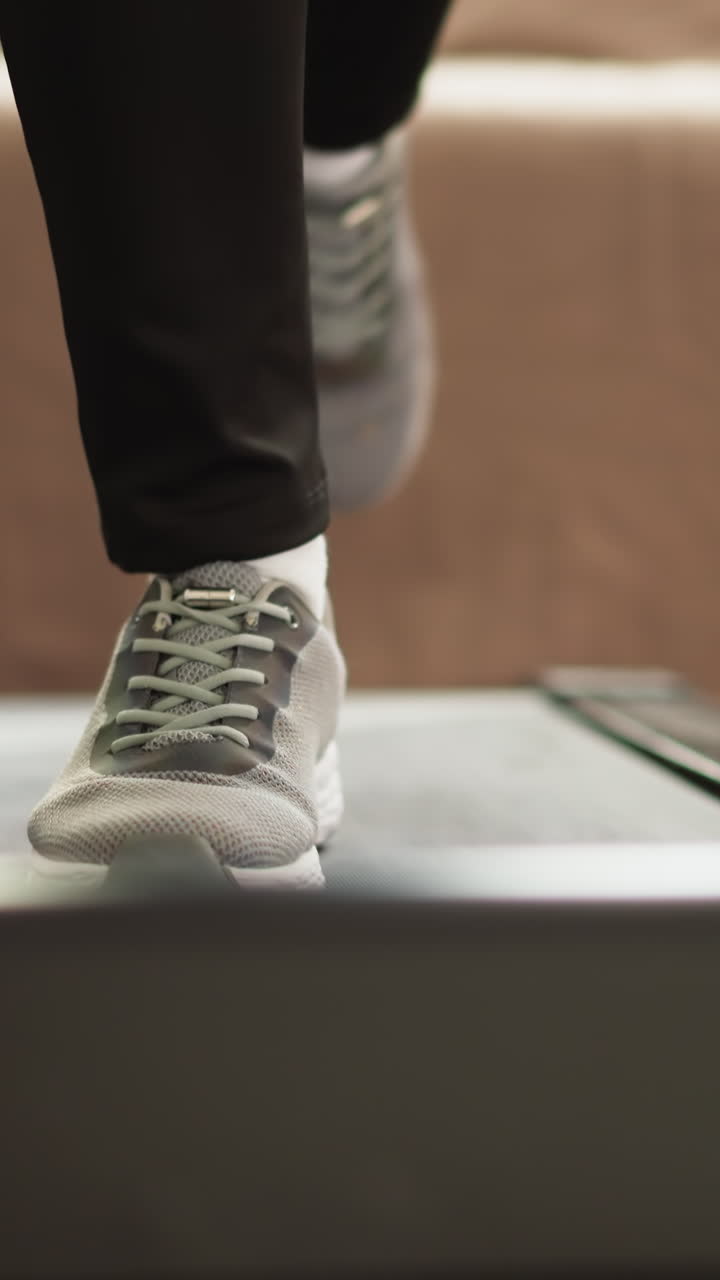 Woman uses treadmill for exercises at home closeup. Fit lady sustains health by executing with legs exercises on mechanized contraption in exclusive gym