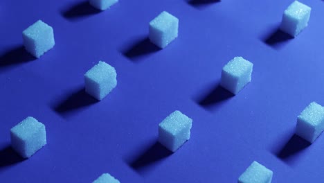 a 4k tilt up view of a unique cubic background with white sugar cubes arranged in rows on a dark blue background, 3d effect