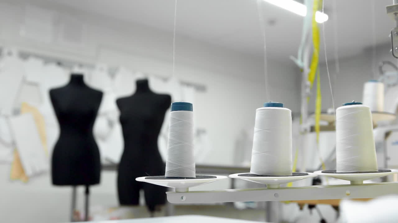 primer plano de tres grandes bobinas con hilo blanco delgado en una máquina de coser profesional en funcionamiento. imágenes de video en tiempo real en alta definición