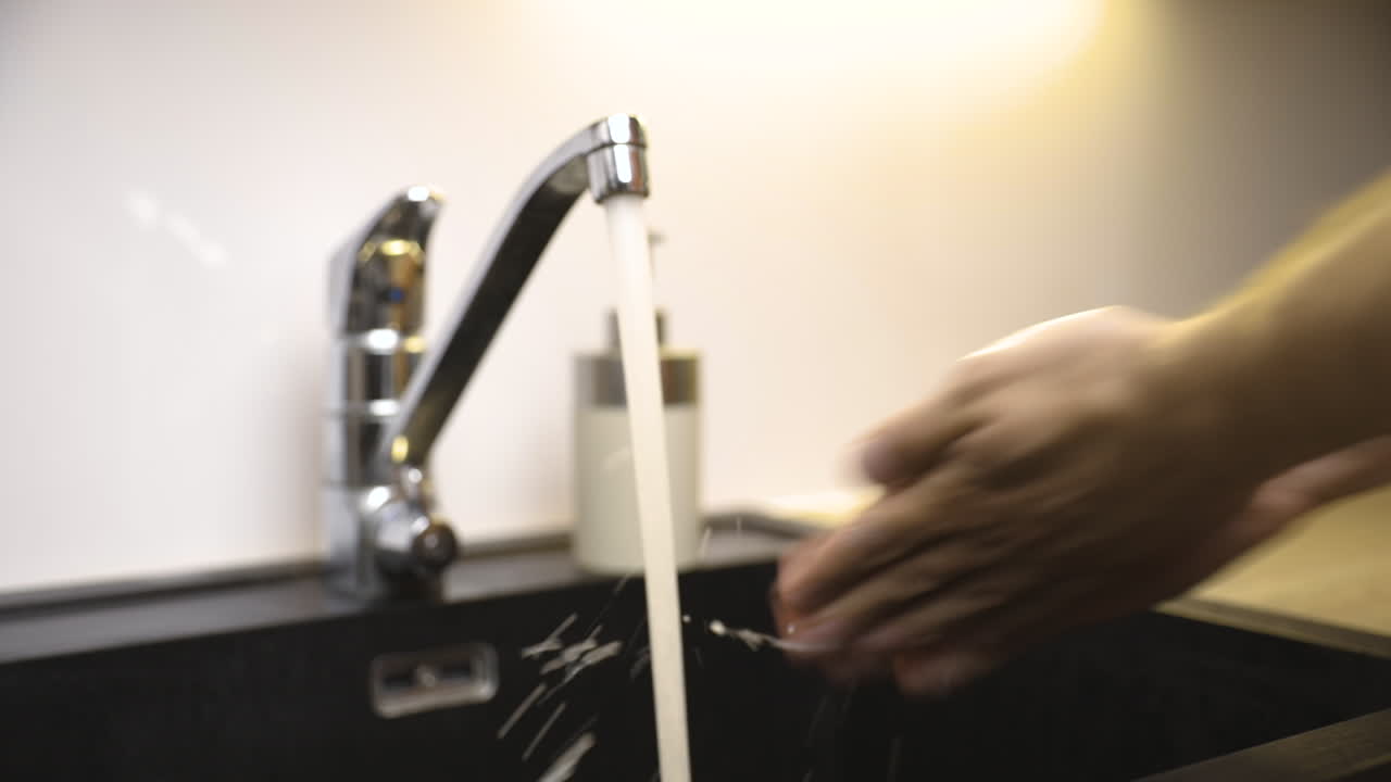 plano general de manos masculinas siendo limpiadas a fondo con jabón junto al grifo