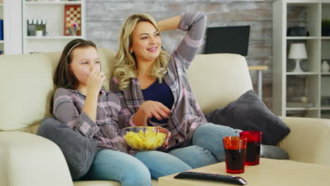 little girl eating chips while watching movie on tv