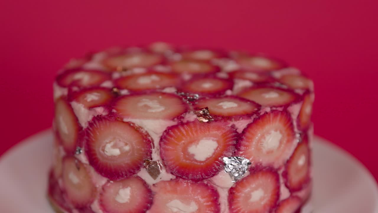 Close-up shot of a strawberry cake set against a bold red background