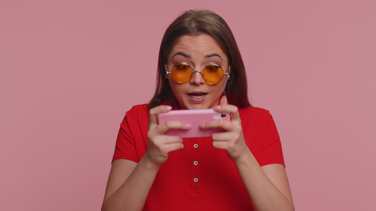 una chica turista adicta y divertida jugando con entusiasmo a un videojuego de carreras en su teléfono móvil