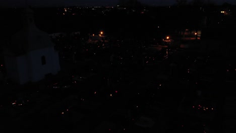 glowing lights and lit grave candles on a dark cemetery during all saints' day