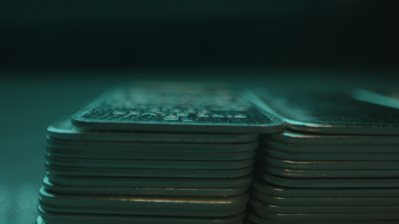 Macro of silver bars in a blue colored room with smoke blowing over the precious metal plates
