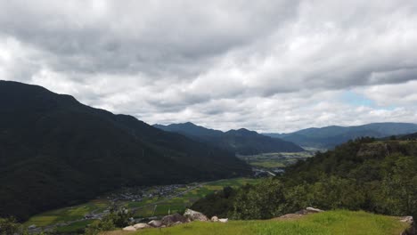 serene pan across city of asago nestled at base of mountains by japanese ricefields