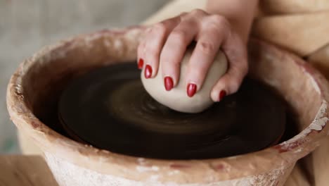 A-close-up-of-hands-working-on-a-ceramic-piece-on-a-pottery-wheel-in-a-clay-studio.-The-artist-uses-her-hands-to-shape-the-clay.-Slow-motion
