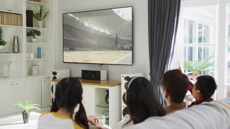 행복 한 가족 이 집 에서 함께 앉아서 tv 에서 장거리 점프 경기를 시청 하고 있다