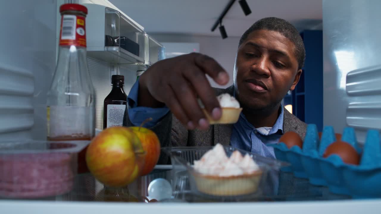 hombre comiendo un pastel del refrigerador por la noche