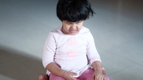 toddler girl sitting on the floor looking sad