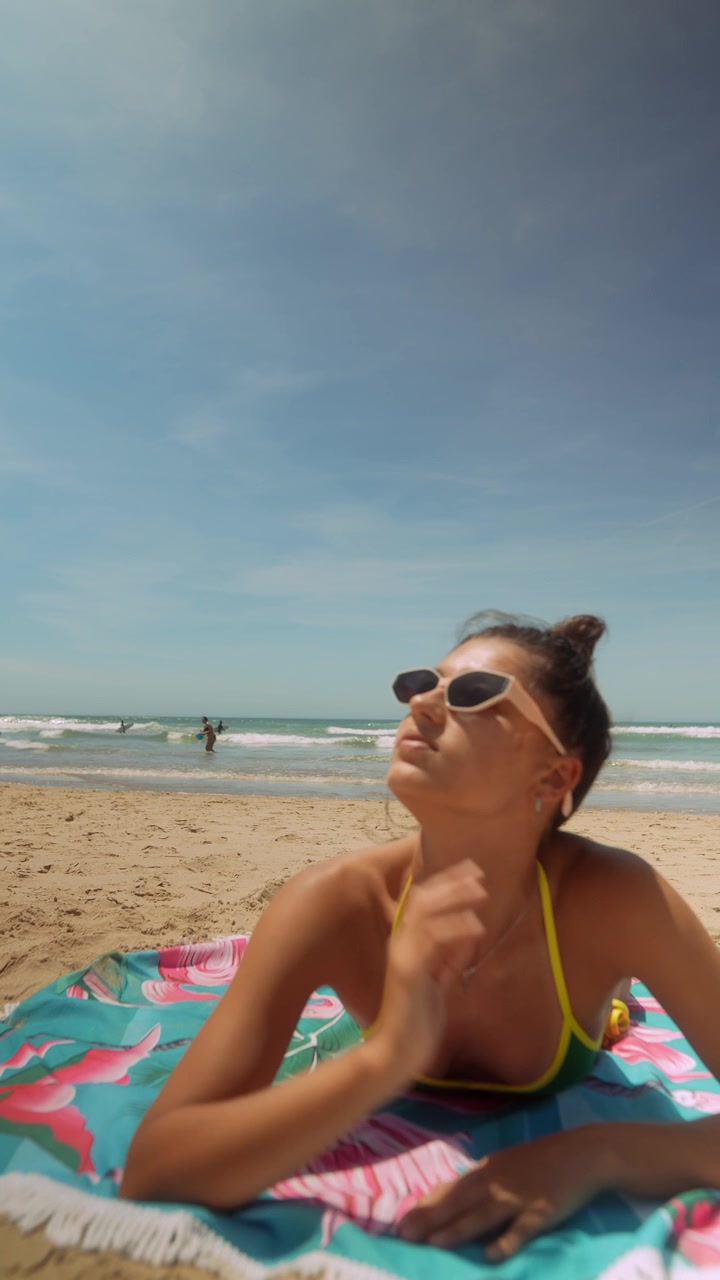 Young Woman Sunbathing on a Beach Towel by the Ocean