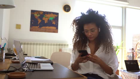 serious black businesswoman using smartphone at home