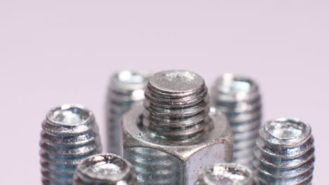 rotating group of galvanized metallic screws close-up. steinless steel bolts isolated on white background.