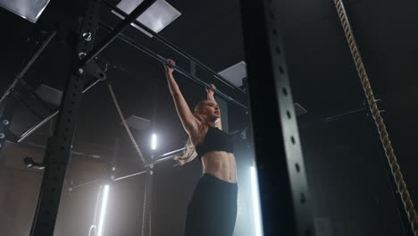una atleta fuerte está haciendo flexiones en el entrenamiento de gimnasia sola por la noche en una sala de fitness oscura