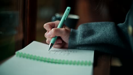 mujer escribiendo en un cuaderno en un café