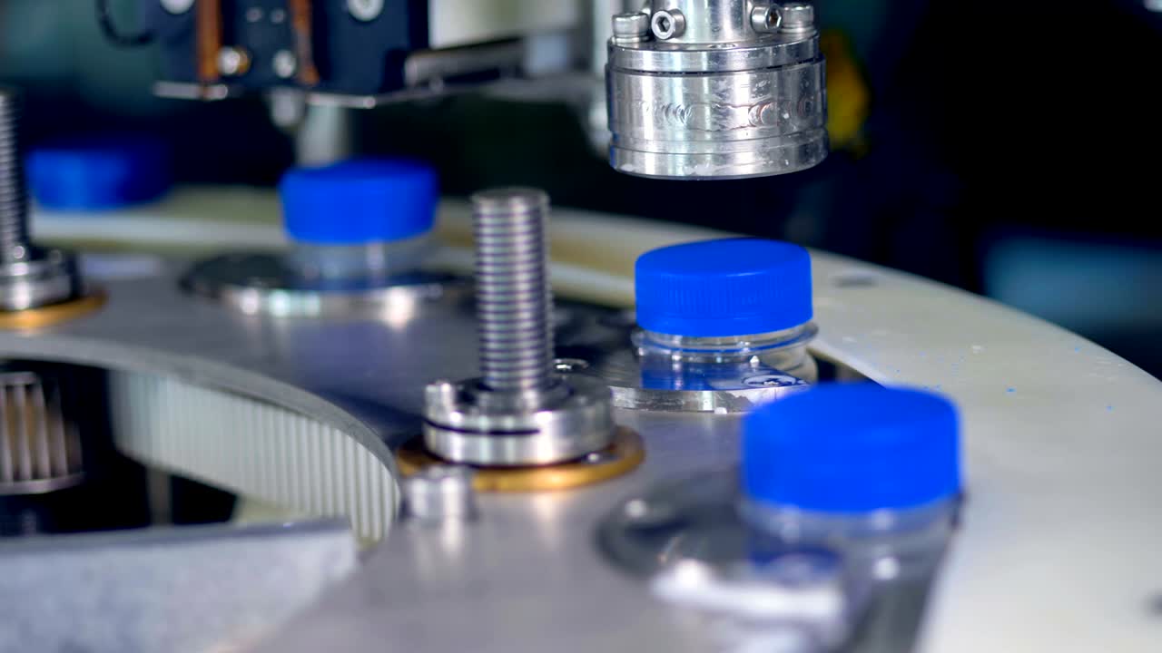 Macro view on milk bottles receiving blue caps.