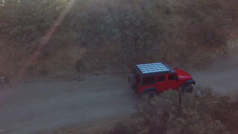 incredible aerial of red jeep driving fast, offroad trail, desert hill landscape