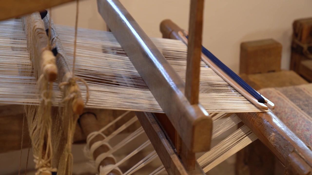 Traditional old weaving loom with white yarn and a blue shuttle