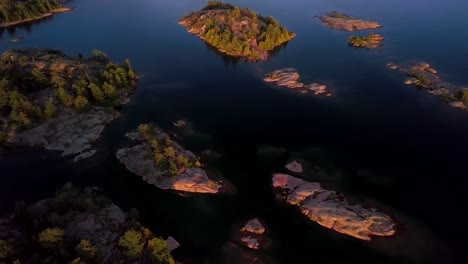 islas rocosas de granito con pinos verdes en el lago azul al atardecer, revelación de inclinación aérea de drones