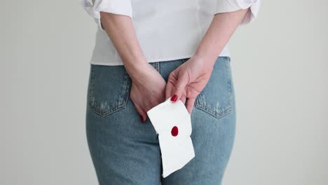 person holding a blood-stained tissue behind their back
