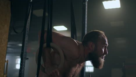 fitness culturismo y el concepto de la gente joven haciendo flexiones en anillos de gimnasia en el gimnasio. guapo joven deportista con pierna artificial haciendo flexiones con anillos colgantes de escalera de gimnasia en el gimnasio