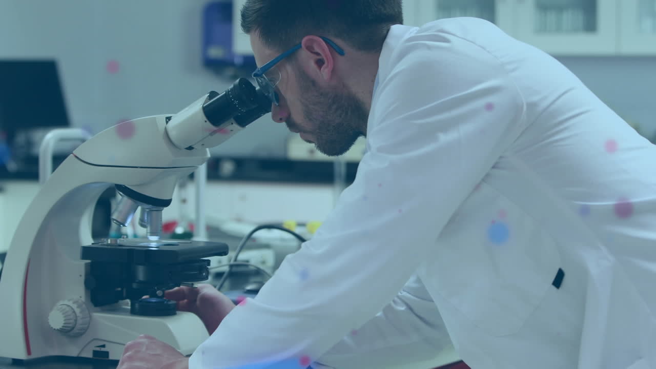 Colorful spots floating against caucasian male scientist using microscope at laboratory
