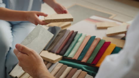 the design team selects finishing materials for their project, compares samples of fabric, wood and wallpaper