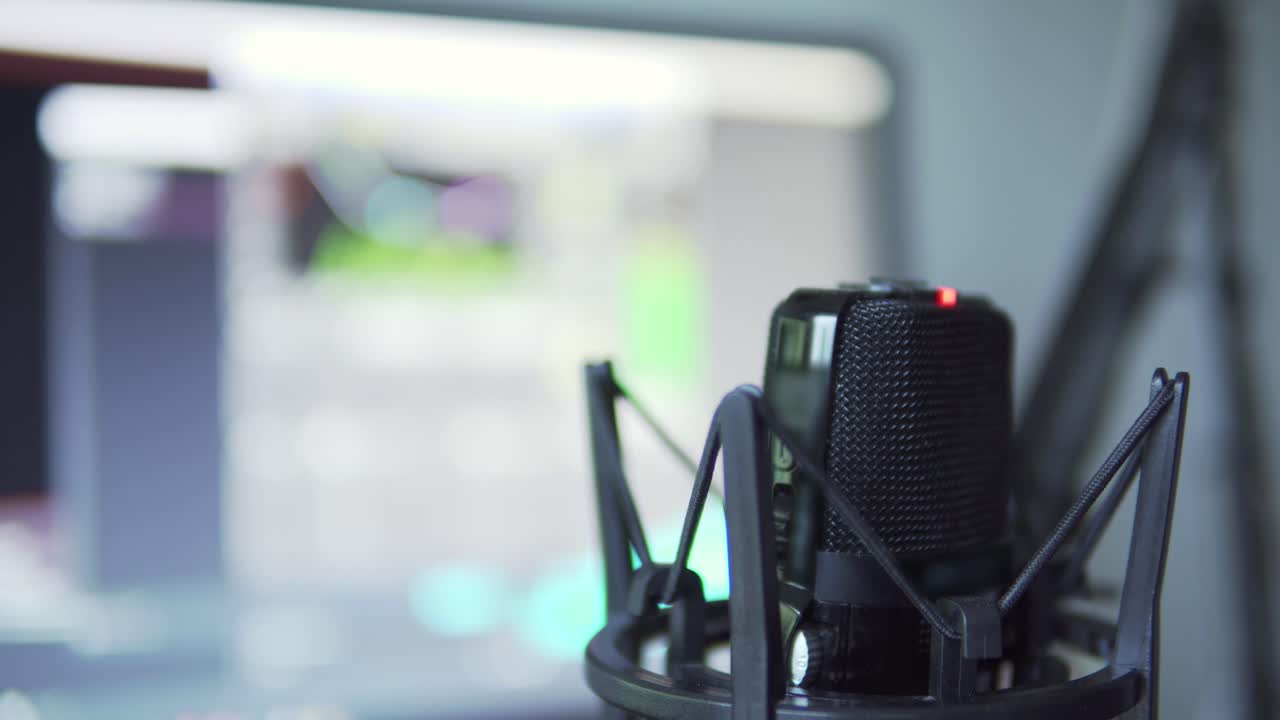 vista de cerca del micrófono profesional mientras habla en el podcast con monitores en segundo plano