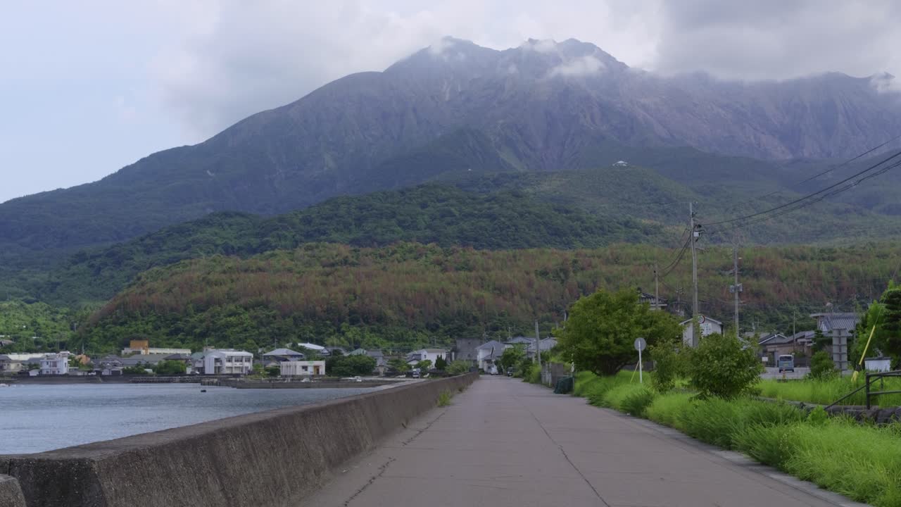 Majestic Sakurajima volcano in distance seen from port town on island