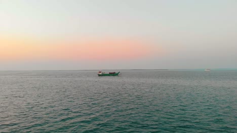 Drohne-Fliegt-Bei-Sonnenuntergang-In-Richtung-Grünes-Boot-Im-Persischen-Golf