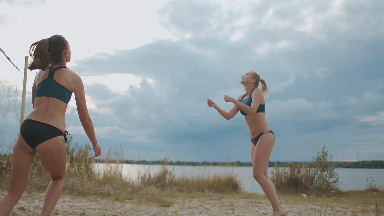 las jugadoras de voleibol de playa pasan la pelota y atacan el partido amistoso de dos equipos femeninos en un día de verano.