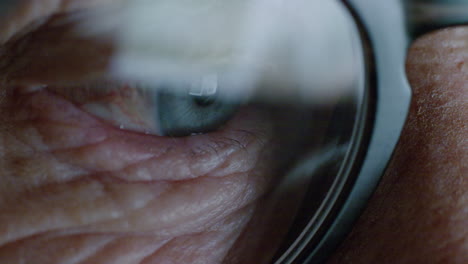 pantalla de ojo macro de cerca que se refleja en las gafas anciana navegando en línea por la noche