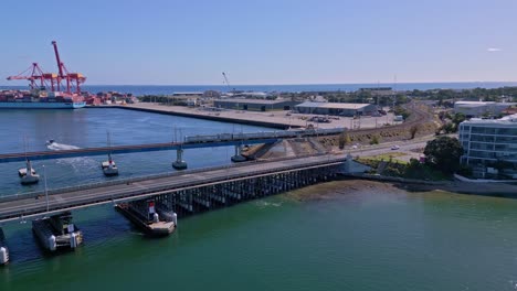 el tren cruza el puente ferroviario de fremantle con el puerto de contenedores en el fondo, perth, australia occidental