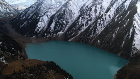 aerial tilt shot overlooking the big almaty lake and snowy mountains of kazakhstan