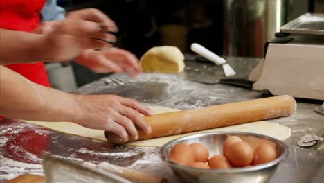 Male-and-female-baker-interacting-while-rolling-dough-4k