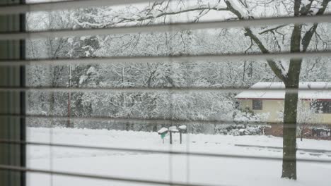 Aus-Einem-Fenster-Mit-Jalousien-Schauen,-Während-Es-Schneit