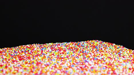 sprinkles scatter and settle against a dark background