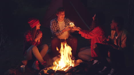 friends celebrating birthday by campfire