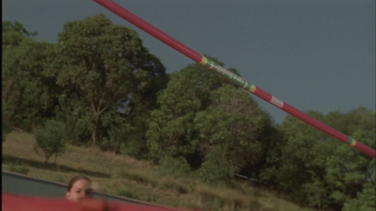 una mujer joven hace un salto alto sobre una barra