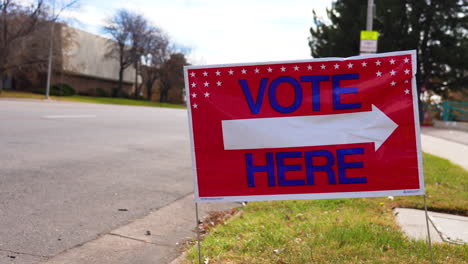 vote here sign pointing right next to empty road, close up