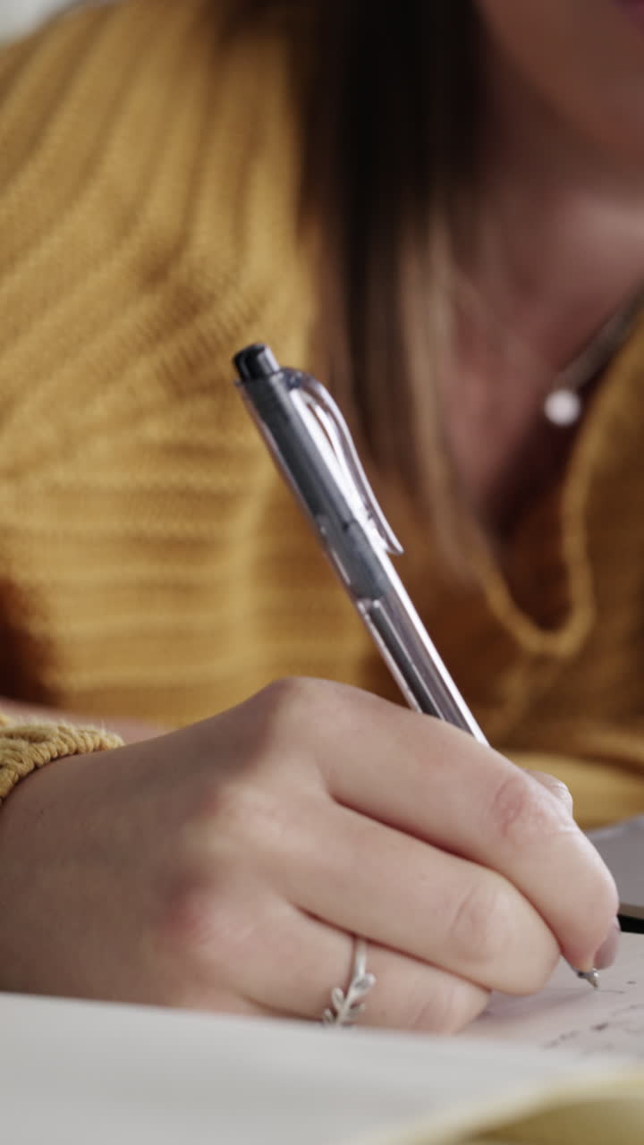 Mujer joven escribiendo en cuaderno mientras usa laptop en casa