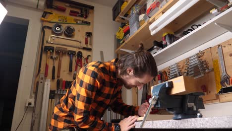 Der-Junge-Kaukasische-Hipster-Mit-Kariertem-Hemd-Bastelt-In-Seiner-Garage-Holz