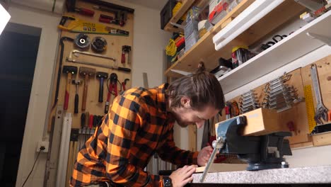 Young caucasian hipster with checkered shirt is wood crafting in his garage