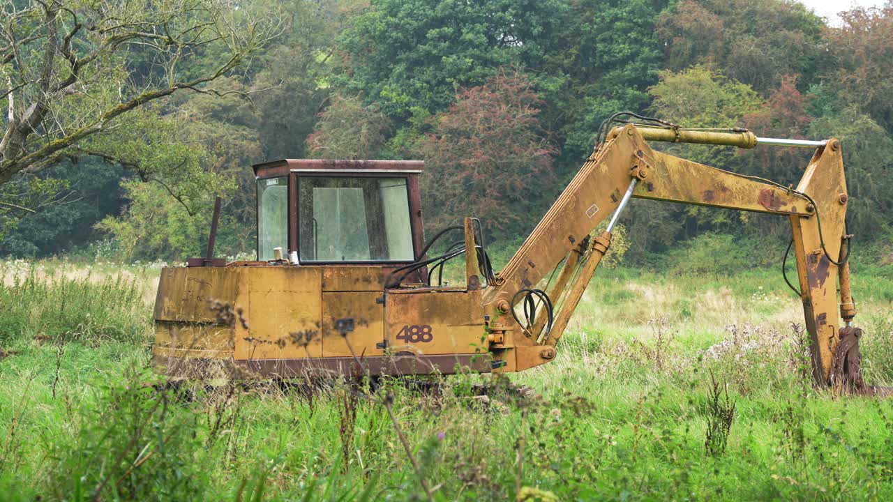 excavadora oxidada en un campo cubierto de vegetación, en la inglaterra rural
