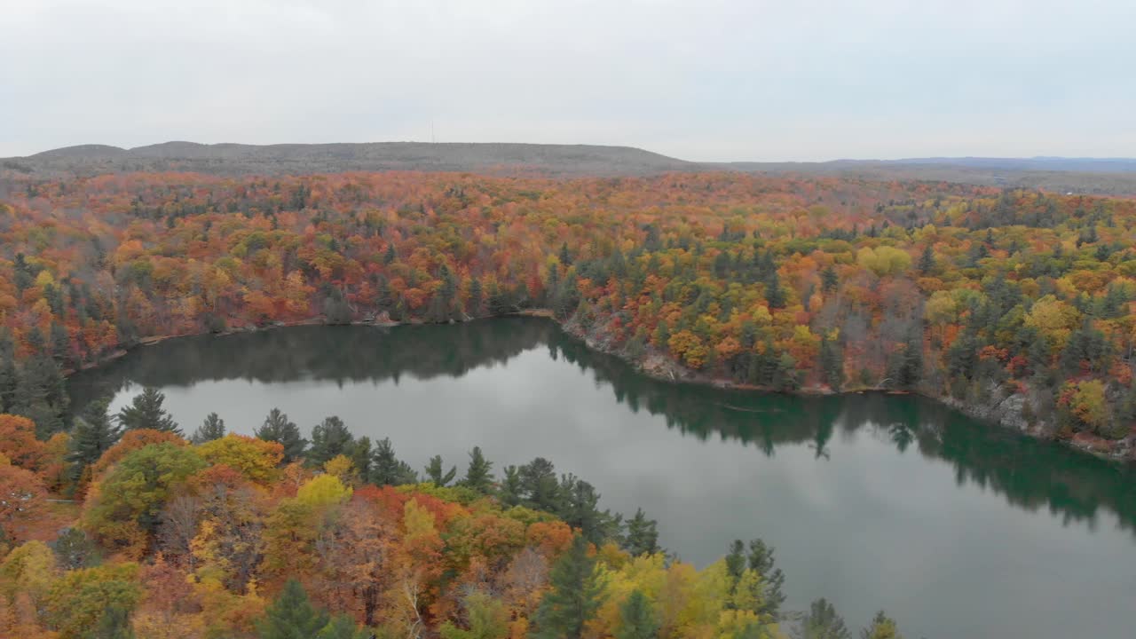 imágenes aéreas laterales sobre el lago rosa en gatineau quebec con las montañas al fondo y naranjos otoñales por todas partes