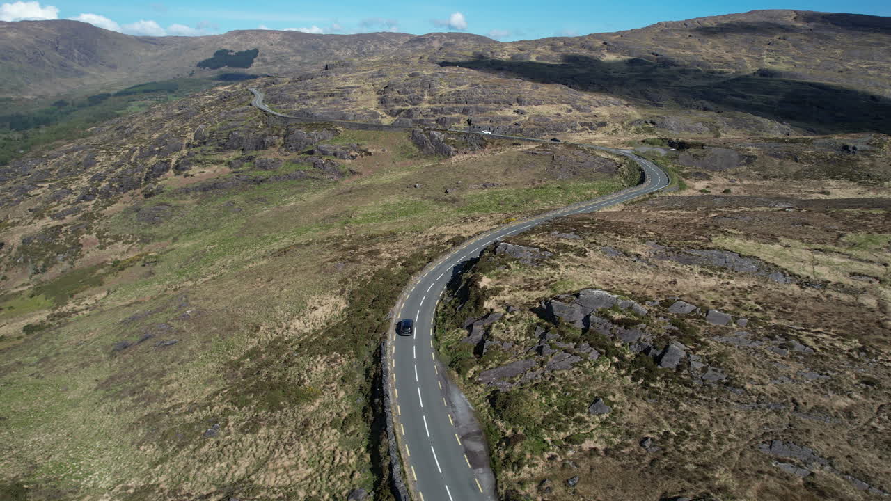 Drone Shot of Black Car Moving on Road in Caha Mountains, Ireland on Sunny Day