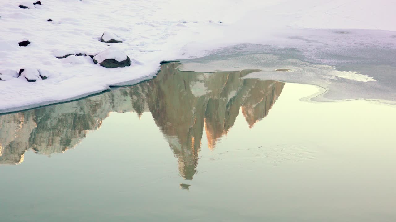 Rocky Torre summit reflected in the frozen waters of Torre Lagoon in Patagonian Andes, El Chalten, Argentina. Static view of lake and mountain covered in snow